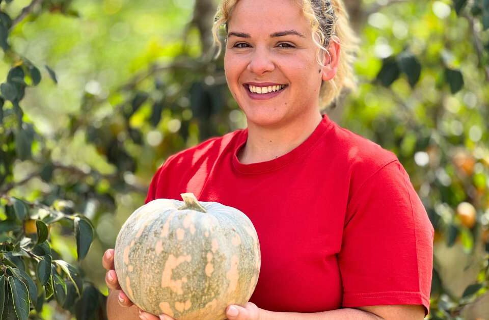 Ragazza sorridente con maglia rossa e zucca in mano