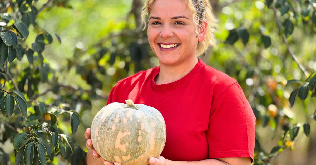 Ragazza sorridente con maglia rossa e zucca in mano