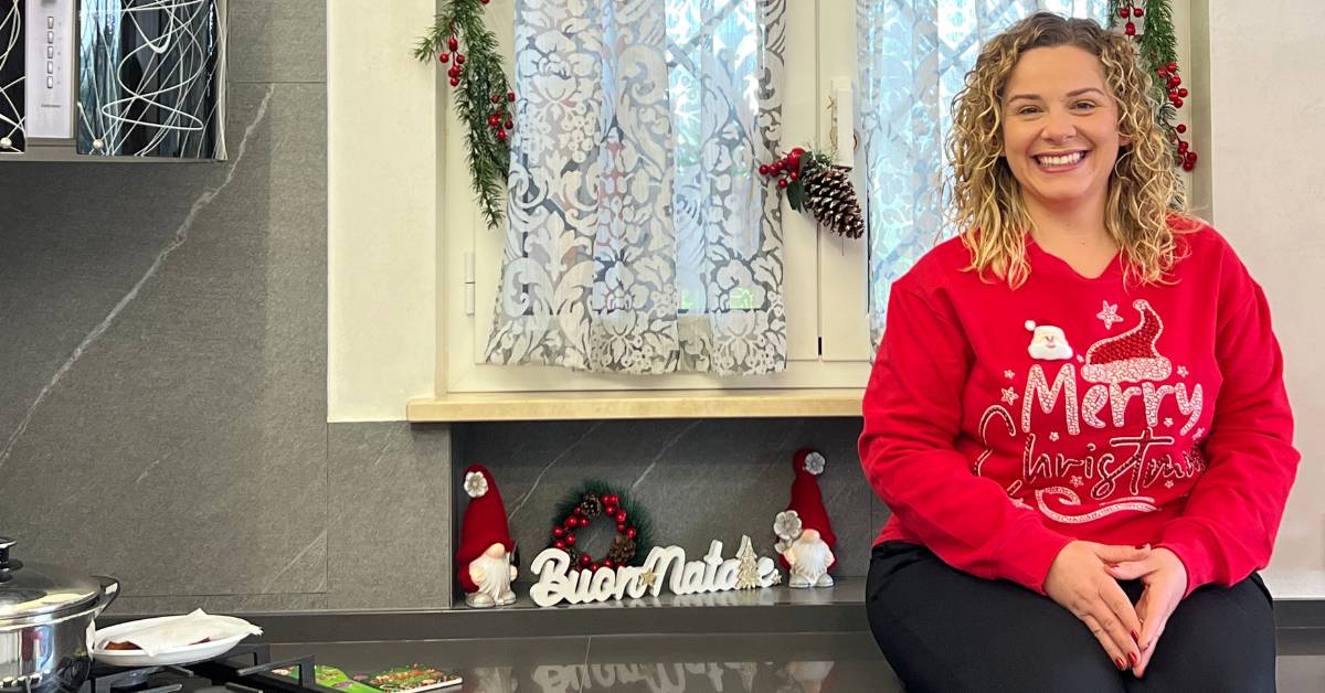 Ragazza con maglia rossa natalizia seduta sul banco della cucina addobbata