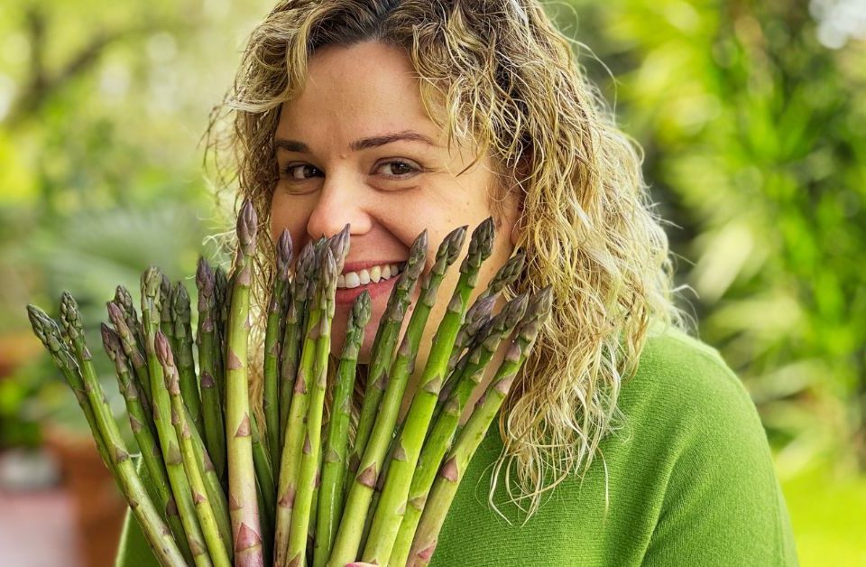 Valentina sorridente dietro un mazzo di asparagi aperti come un ventaglio