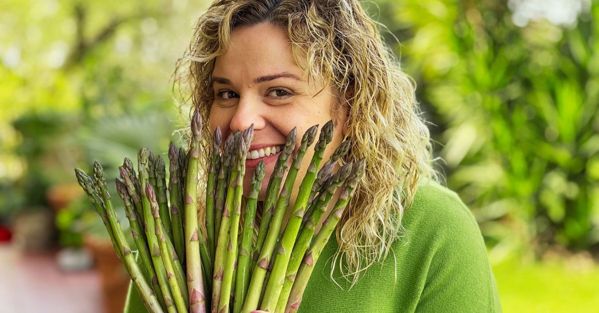Valentina sorridente dietro un mazzo di asparagi aperti come un ventaglio