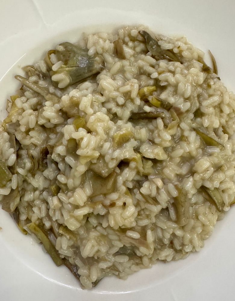 Risotto con i carciofi su piatto bianco