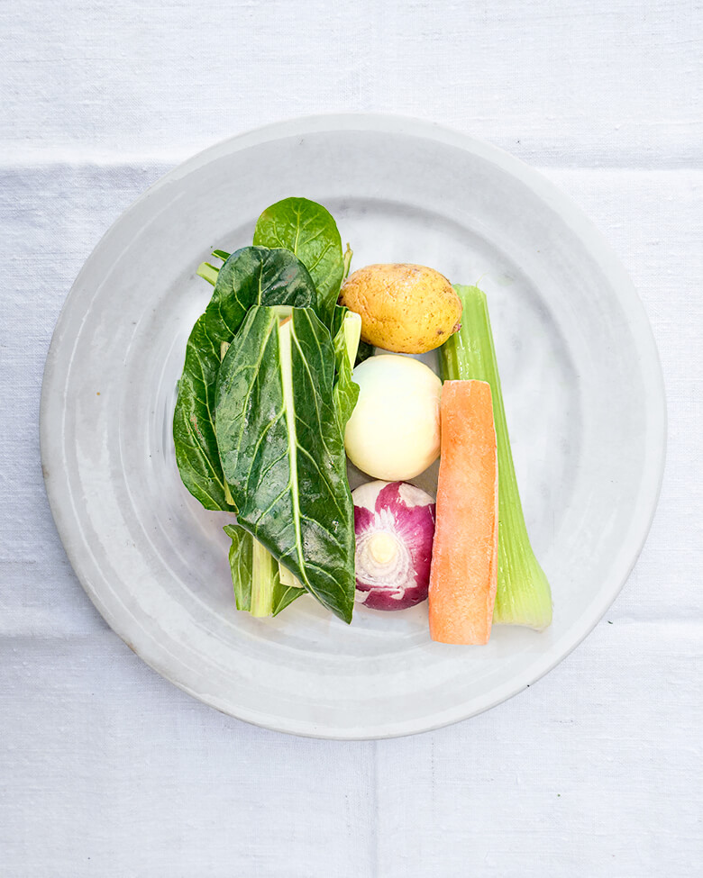 Piatto di verdure miste per il preparato del brodo vegetale. Foglie di bieta, cipolla di tropea, carota, patata, cipolla bianca e sedano